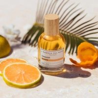 Flakon von Orange Verte Eau de Parfum neben frischen Orangenscheiben und Palmblättern.