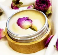 Festes Parfüm Ko mit getrockneter Rose in eleganter Bambusverpackung, umgeben von Blüten