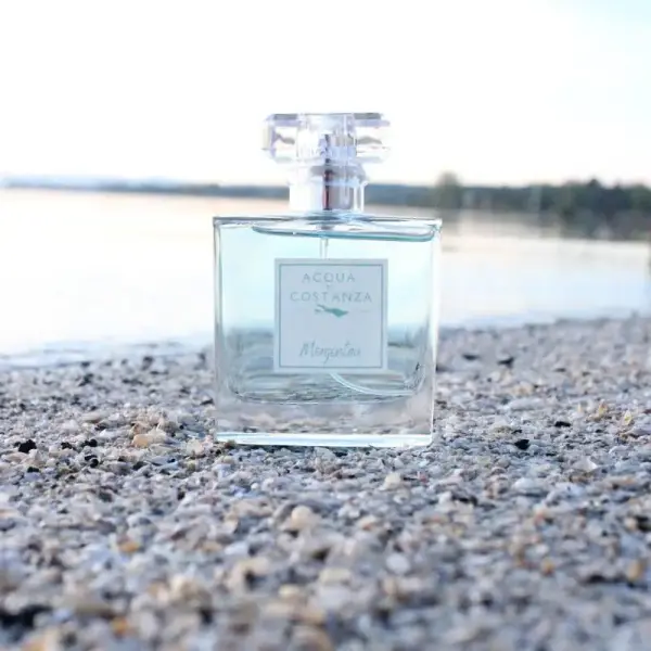 Acqua di Costanza Morgentau Damen Parfum Flakon auf kieseligem Bodenseestrand, hellblaue Flüssigkeit, frischer Duft.
