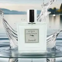 Acqua di Costanza Seensucht Unisex Parfum Flakon umgeben von Wasserfontänen und Tropfen, mit dem Bodensee im Hintergrund bei Dämmerung, belebender Duft.